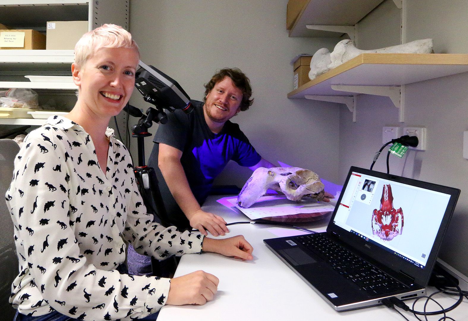 Two people sitting at a desk with a computer in front looking at 3D models